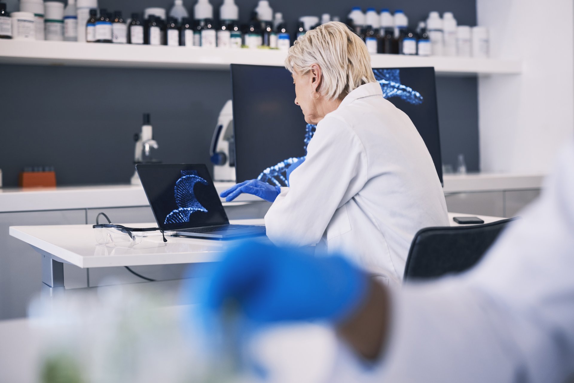 Scientist, computer screen and DNA research, genetics analysis and study in medical laboratory. Doctor or woman on laptop for virus, vaccine and genes results, solution and science for healthcare.
