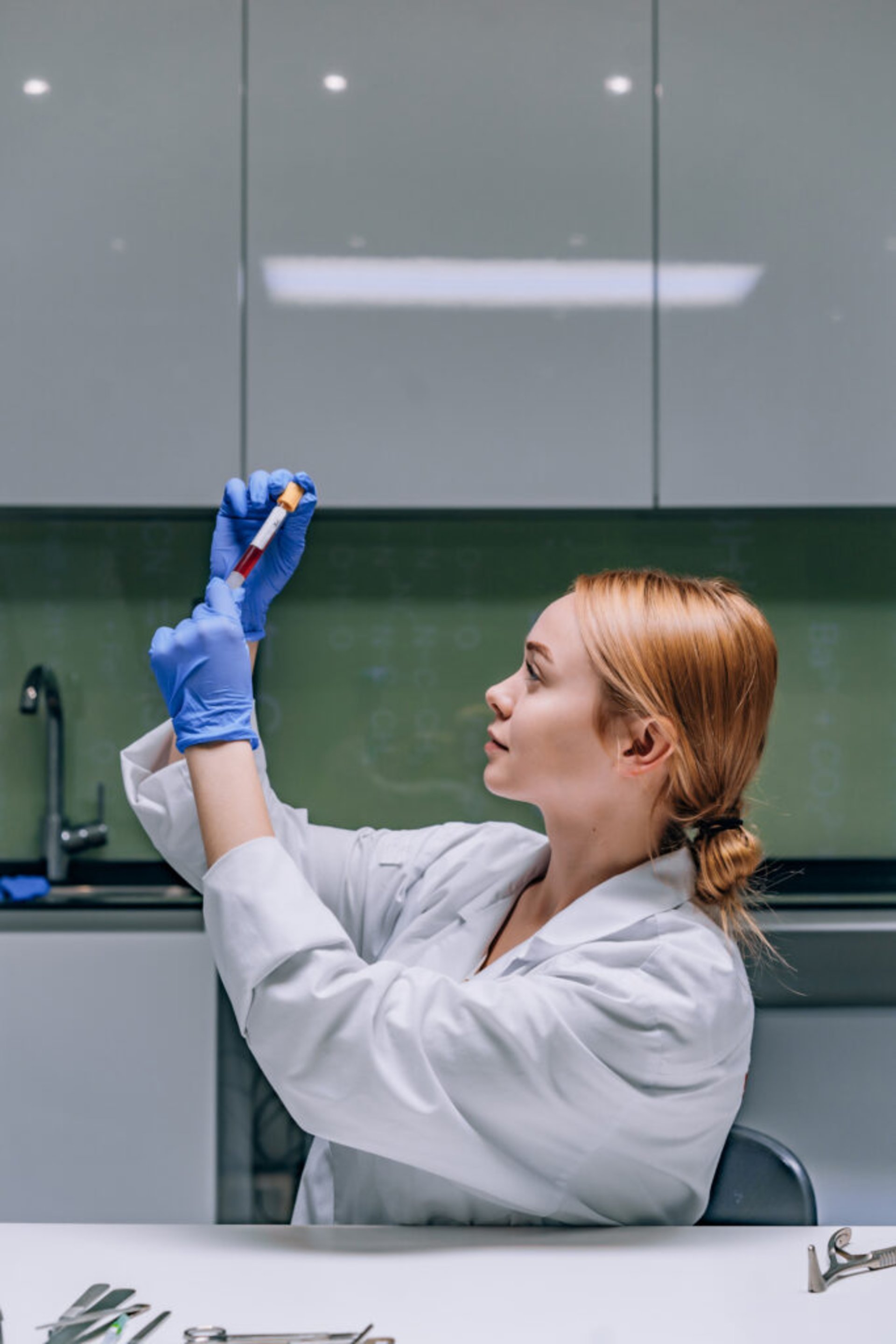 Female medical or scientific researcher or woman doctor looking at a test tube of clear solution in a laboratory.